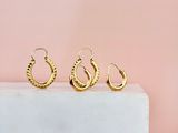 une paire de boucles d'oreilles en anneau en or posée sur un bloc de marbre