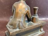 bronze statue of a woman sitting on a bench with a vase in her lap