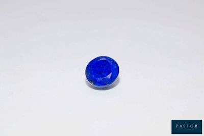a blue sapphire stone on a white surface