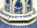 a blue and white vase with a bird on top of it