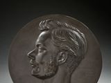 a close up of a bronze plate with a man ' s face