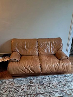 un canapé en cuir marron dans un salon où se trouve un tapis au sol