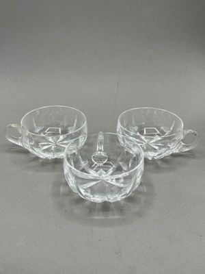 three clear glass cups and saucers sitting on a table