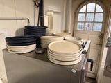 many plates stacked on top of a microwave in a kitchen