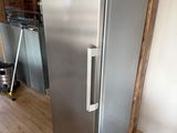 un réfrigérateur argenté au milieu d'une pièce au sol en parquet