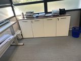 une photo d'une pièce avec un bureau, des armoires et une fenêtre