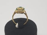 an image of a gold ring with a green stone in it