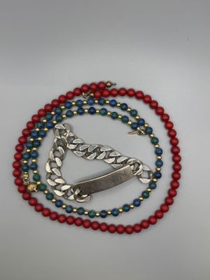 collier de perles rouges, blanches et bleues orné d'un pendentif en forme de poisson
