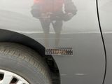 a man standing in front of a car with a measuring tape on the door