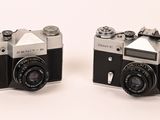 pair of black and silver cameras sitting on a white surface