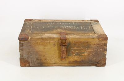 an old wooden box with writing on it sitting on a white surface