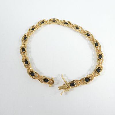 un gros plan d'un bracelet en or orné de pierres noires