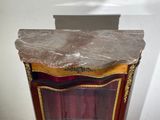 a marble top display case with a red curtain behind it