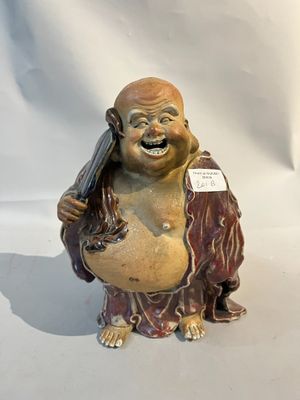 une statue représentant un Bouddha souriant tenant un téléphone portable