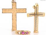 two gold crosses and a pink stone ring on a white surface