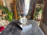 a silver vase sitting on a table with a mirror in the background