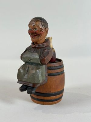 a small wooden figurine of a man sitting on a barrel