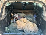 the back of a car with a bed and blankets in the trunk