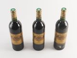 three bottles of wine sitting next to each other on a white surface
