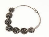 a close up of a bracelet with black beads on a white background