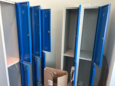 plusieurs casiers bleus dans une pièce, avec une boîte en carton posée devant eux