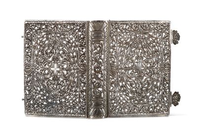 a silver plated book with intricate designs and a tassel