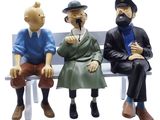 three figurines of people sitting on a bench