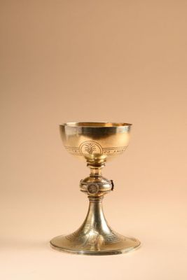 a silver chalicet on a white surface with a brown background