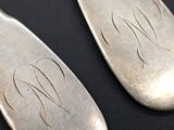 pair of silver spoons with engraved initials on them on a black surface