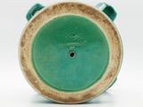 a close up of a green vase on a white surface