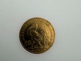 a gold coin with a rooster on it on a white surface