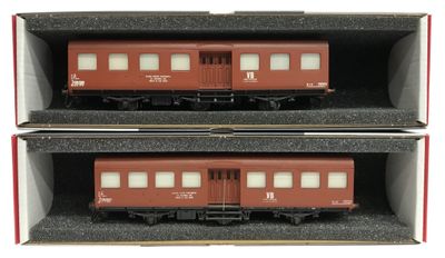 deux trains rouges posés dans une boîte sur une surface blanche
