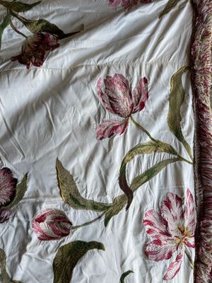 a bed with a white and pink floral comforter on it
