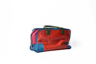 un sac à main rouge et bleu posé sur une surface blanche