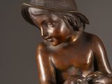 bronze statue of a boy with a hat holding a cat