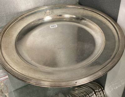 a silver plate sitting on a glass shelf next to a stack of silverware