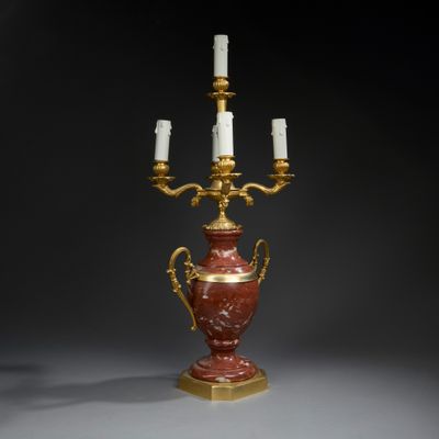une image représentant un vase rouge et doré sur lequel sont posées trois bougies
