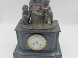 statue représentant une femme avec deux enfants et une horloge posée sur une table