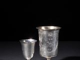 silver goblet and cup on a black surface with a black background