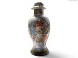 un vase muni d'un couvercle posé sur une surface blanche