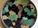 une assiette décorative ornée de feuilles, accrochée au mur