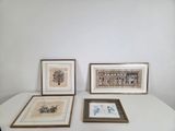 three framed pictures on a table in a room with a white wall