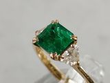 a close up of a ring with a green emerald stone