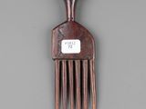 a wooden comb with a tag on it on a gray surface
