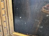 an image of a close up of a gold frame with a painting in the background