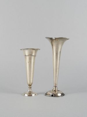 une paire de vases en argent posés sur une surface blanche