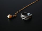 a close up of a ring and a pearl on a black surface