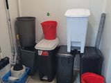several buckets and mops are lined up in the corner of a room