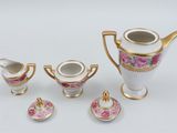 a white and gold tea set with pink flowers on it