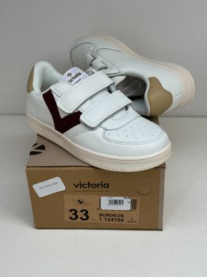 des baskets blanches et bordeaux à velcro, posées sur une boîte en carton
